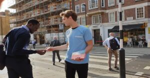 Homem entregando panfleto na rua para outra pessoa